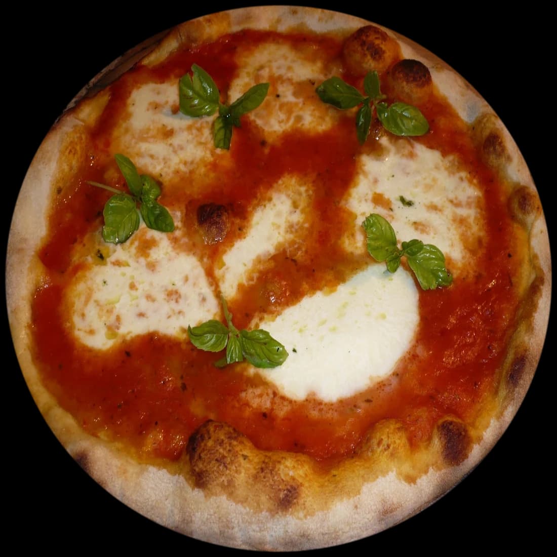 A round margherita pizza with basil, seen from above