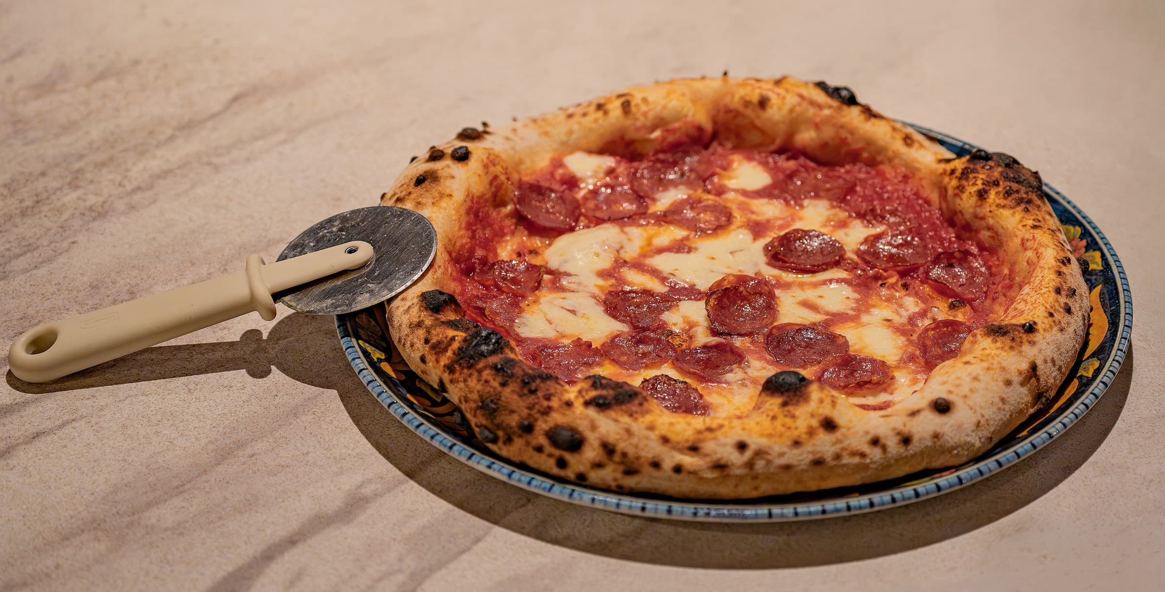 A Neapolitan-style pizza with a charred, puffy crust, fresh from a wood-fired oven