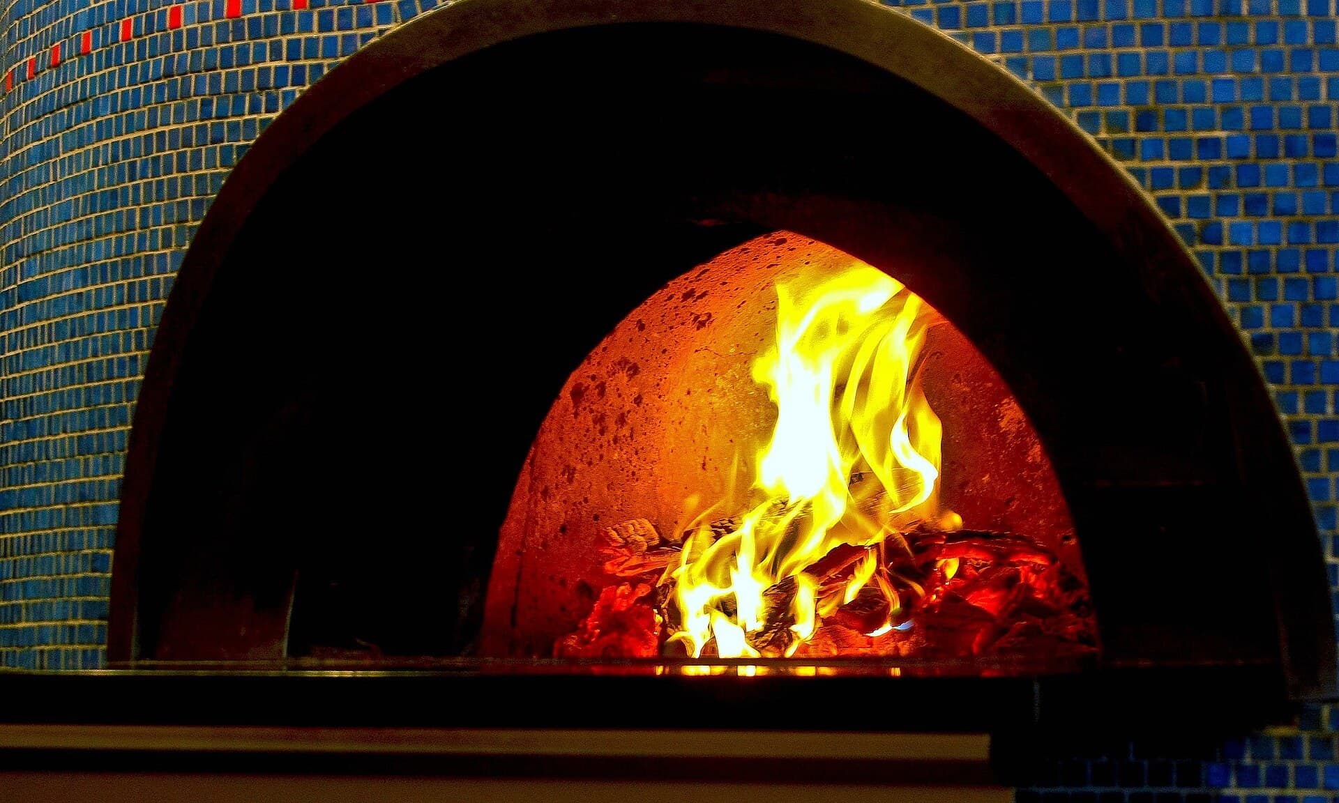 Flames inside a tiled commercial pizza oven, seen through the oven mouth